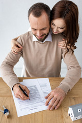 Naklejka premium happy man holding pen near document with rental agreement lettering and cheerful woman