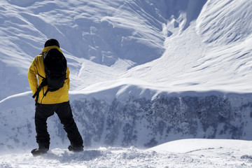 Snowboarder on top of snowy off-piste slope at windy winter day