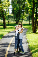 Picture of brother and sister having fun in the summer park on sunset. Cheerful children hugs and laughing. Little girl and boy playing outdoors, best friends, happy family, love and happiness concept