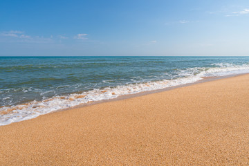 Fototapeta na wymiar Empty summer beach with golden hot sand and splashing waves