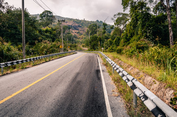 Winding mountain asphalt road through the autumn forest in Khao Laem National park in Kanchanaburi Province of Thailand.