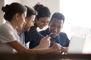 Smiling diverse colleagues laugh brainstorming using laptop