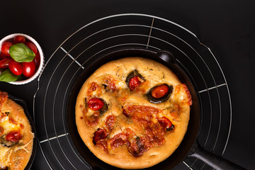 Food concept fresh baked Homemade organic Focaccia in skillet iron pan on black background with copy space