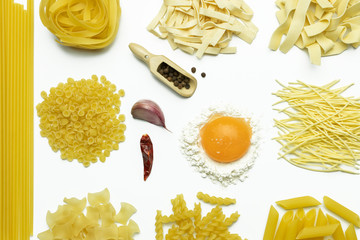 Ingredients for cooking pasta on white background. Fettuccine, tomatoes, spices, flour and egg. Italian food concept. Flat lay, top view.