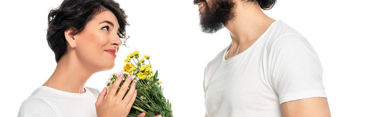 Fototapeta premium panoramic shot of cheerful latin man giving flowers to attractive woman isolated on white