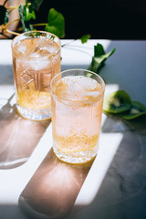 A glass of pink wine in a crystal glass on a marble background, green ivy and bright sun