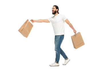 happy latin man holding shopping bags while walking isolated on white