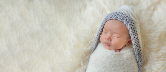 Adorable newborn baby sleeping in cozy room. Cute happy infant baby portrait with sleepy face in...