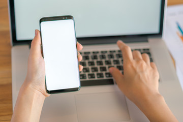Business woman hand with Financial charts and mobile phone over laptop on the table .