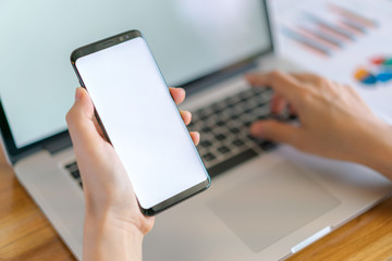 Business woman hand with Financial charts and mobile phone over laptop on the table .