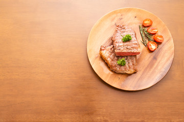 Fresh cooked half cut beef sirloin with cherry tomato and rosemary on top with parsley, Wood background, Copy space on the left