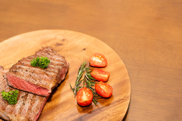 Fresh cooked half cut beef sirloin with cherry tomato and rosemary on top with parsley, Wood background, Copy space on the right