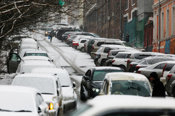 Cars drive along a snowy road in the snowfall in winter. Road traffic in the winter season.