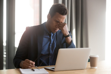 Obraz premium Tired black businessman take off glasses suffering from headache