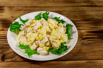 Festive salad with chicken breast, sweet corn, canned pineapple and mayonnaise on wooden table