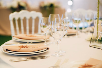 Wedding table service. Plates, glasses and flowers served on pink cloth