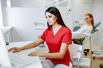 smart charming woman dentist sitting on computer desk with his hand read document, smile and looking at camera