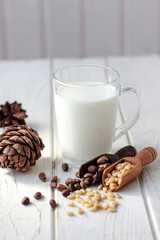 Cedar milk with pine nuts over white wooden table.