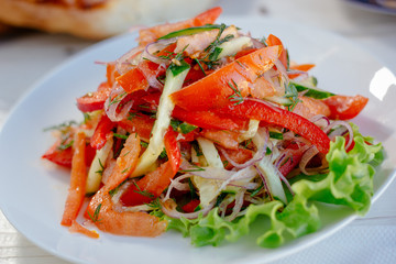 Vegetable salad on the white plate. Achik Chukchuk salad with tomatoes and onion.