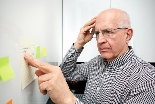 Elderly man with dementia looking at notes