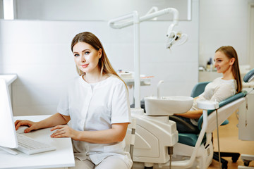 smart charming woman dentist sitting on computer desk with his hand read document, smile and looking at camera