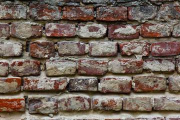 Texture of a very old peeling red brick wall covered with plaster closeup. time breaking background