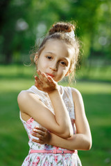 Cute little girl on the meadow in rose dress on sunset. Posing like ballerine. Childhood concept.