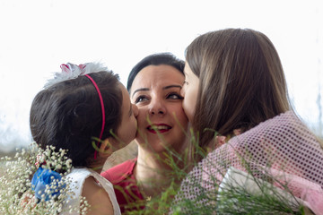 the daughters giving flower and kiss her mother in mothers day