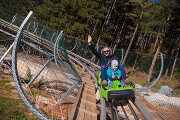 young father and son driving alpine coaster