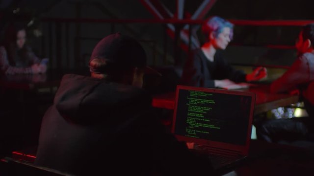 Rare view of hacker sitting in caf&eacute; at laptop and developing new software