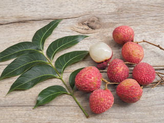 Top view a group delicious red ripe Lychees fruit with green leaves on wood texture background.