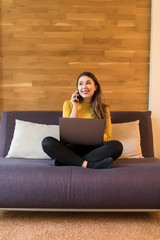 Obraz premium Young pretty woman working on a laptop sitting on bed at home.