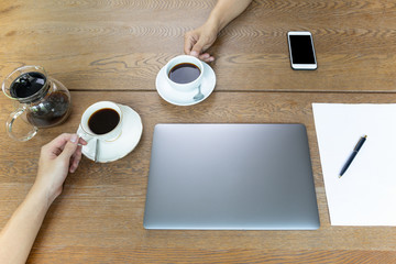 Top view of businessman hands holding coffee cup with laptop on table.