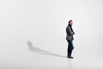 Stylish man isolated on white studio background, eyeglasses, standing full height, with crossed arms, looking at camera. © Dragosh