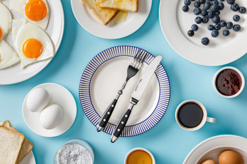 top view of table setting for breakfast on blue background