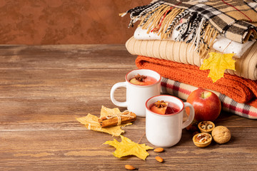 A mug of hot drink and a stack of knitted clothes on a wooden background. Autumn concept. Copy space. Selective focus.