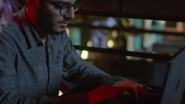 Tilt up of young man and woman sitting at table at laptop. Man typing and woman telling him what to do