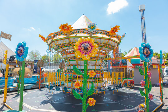 Carousel chains for children in bright colors during a fair in an Italian park flower shaped lights.