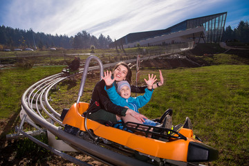 young mother and son driving alpine coaster