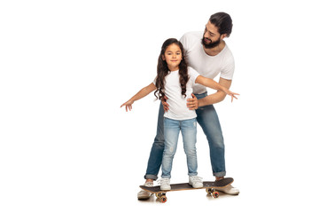 Fototapeta premium happy latin father looking at cute daughter riding penny board isolated on white