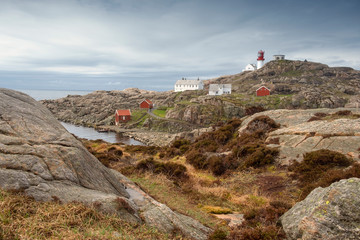 Fototapeta na wymiar Norway in the spring. landscape rocky coast of the northern sea, traditional wooden red Norwegian houses and the southern lighthouse Lindesnes fyr