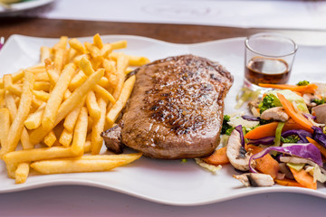 Grilled steak, French fries and vegetables