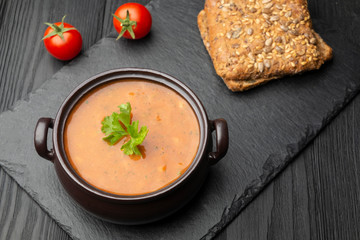 Vegetable soup sprinkled with parsley, two cherry tomatoes, and two slices of bread