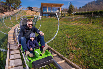 young father and son driving alpine coaster