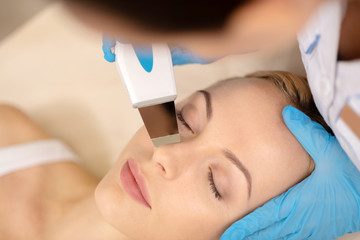 Naklejka premium Young woman closing eyes while having deep facial cleansing