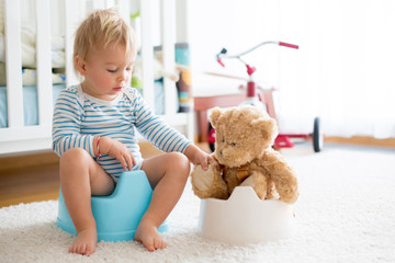 Cute toddler boy, potty training, playing with his teddy bear