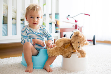 Cute toddler boy, potty training, playing with his teddy bear