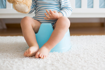 Cute toddler boy, potty training, playing with his teddy bear