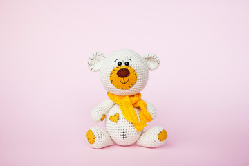 Amigurumi handmade teddy bear isolated on a pink background. Baby background. Copy space
