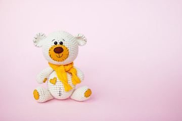 Amigurumi handmade teddy bear isolated on a pink background. Baby background. Copy space